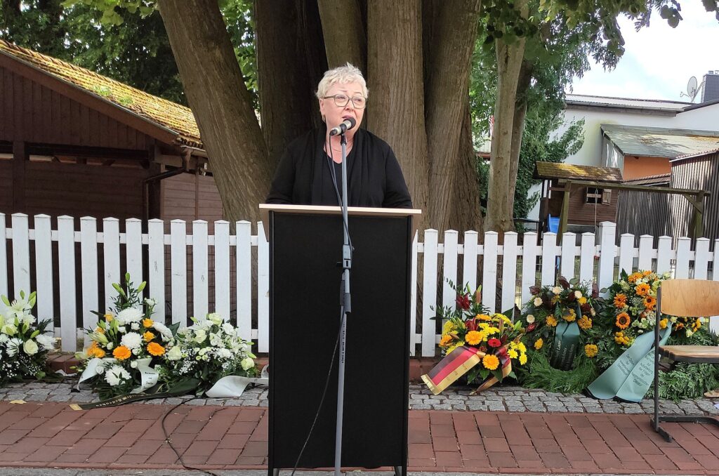 Frau hält Rede, um den Opfern der Malchower Werwolf-Tragödie zu gedenken.